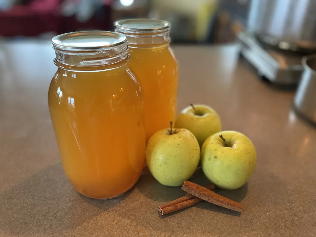 canned apple cider with apples and cinnamon sticks